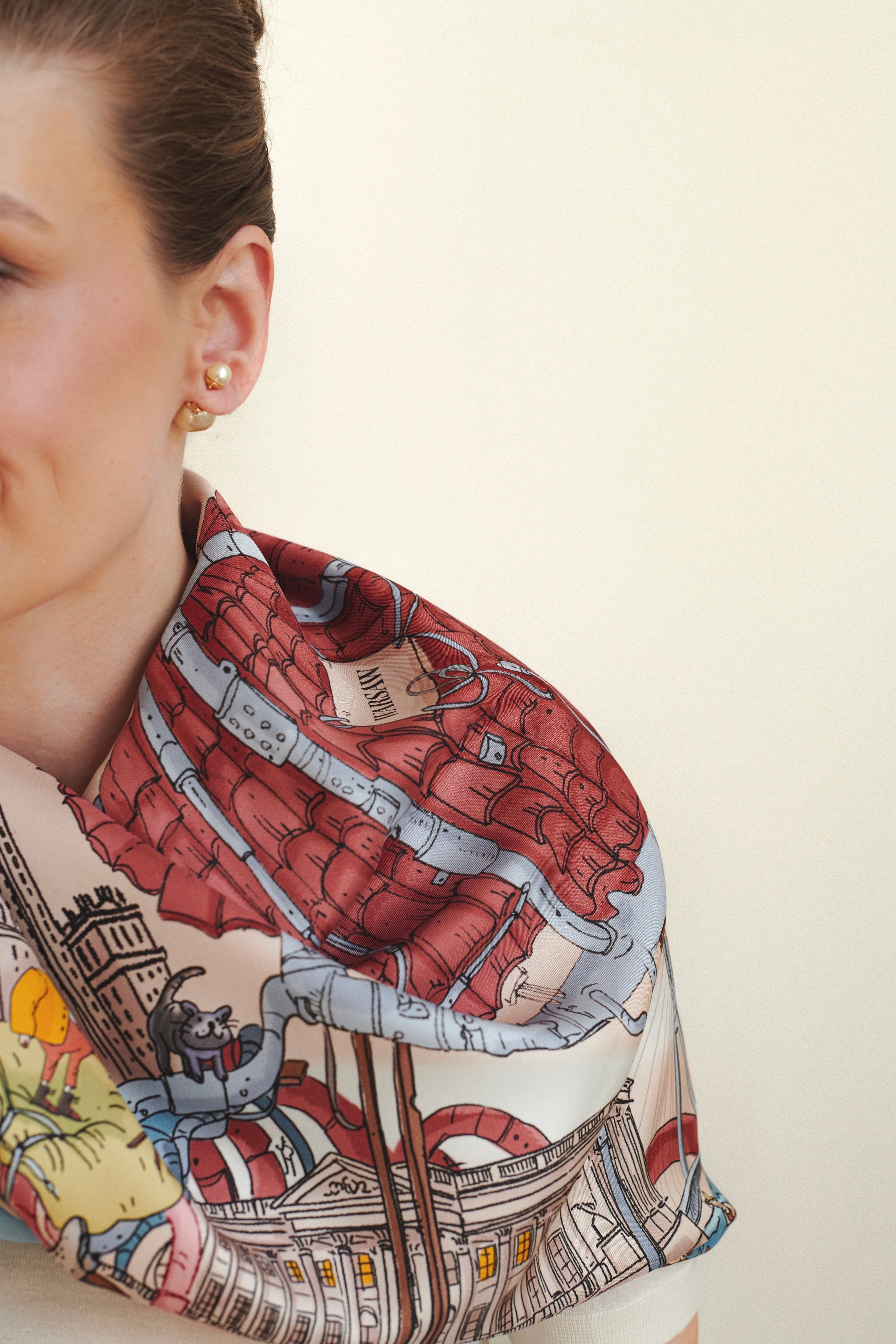 Person wearing a colorful scarf with architectural design on a plain background