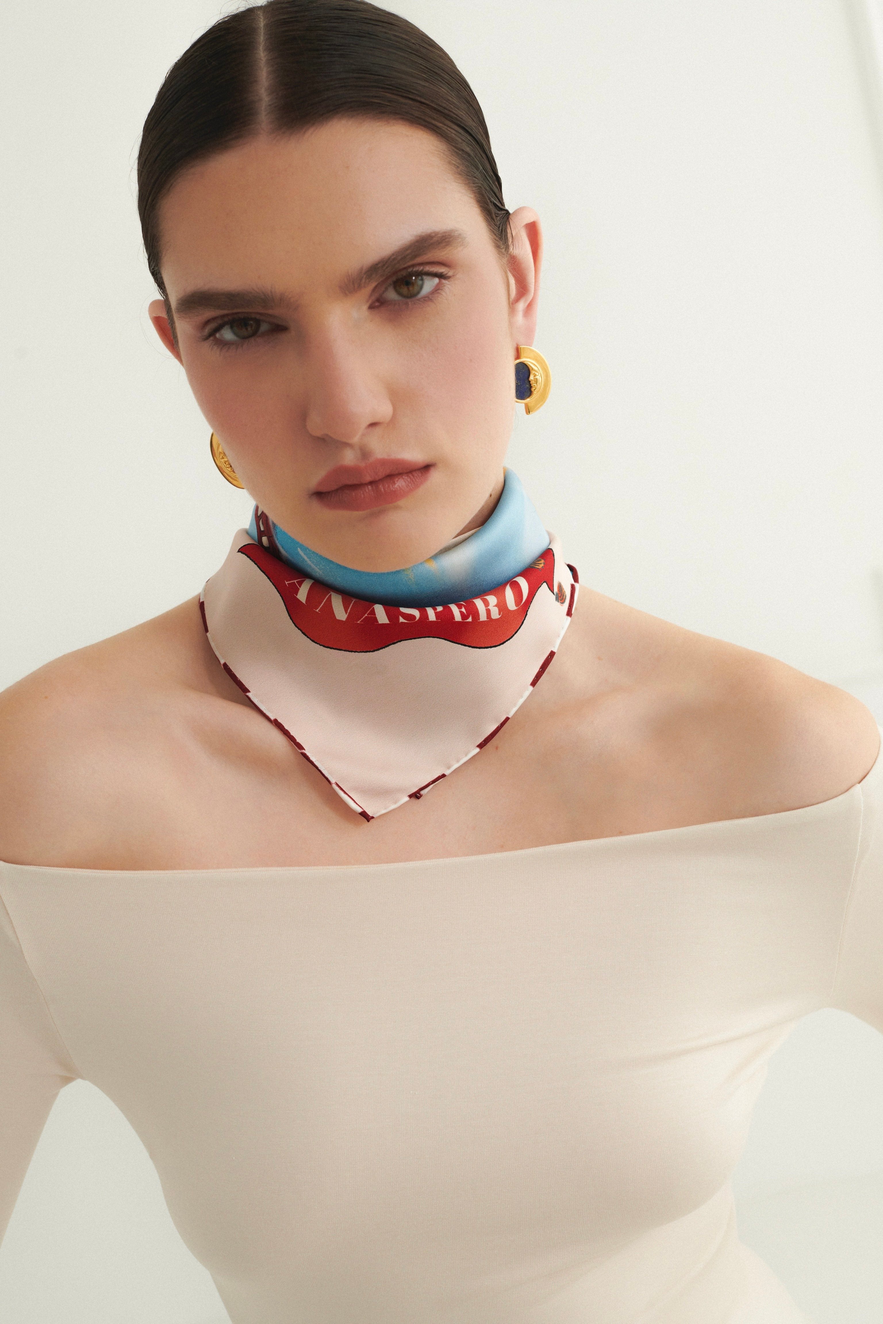 Woman wearing a colorful scarf with a visible brand logo against a white background
