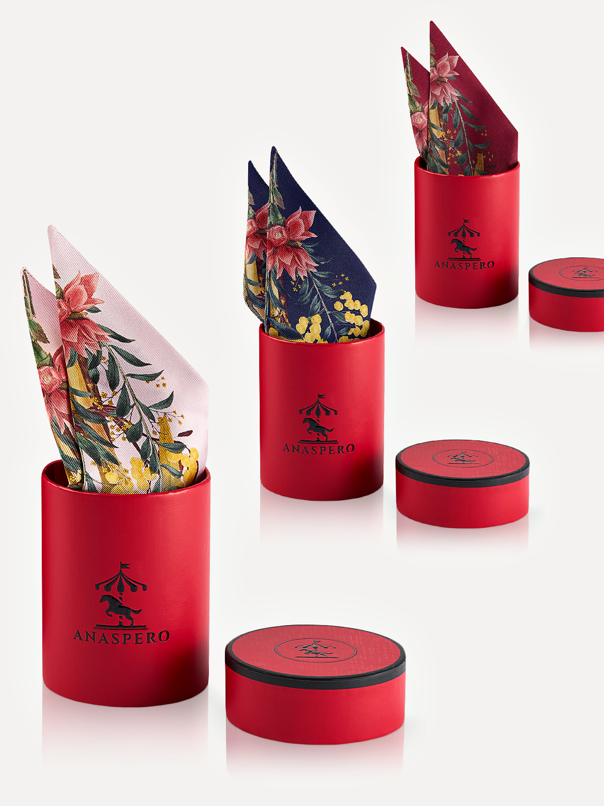 Three red Anaspero cylindrical boxes with floral silk twilly on a white background